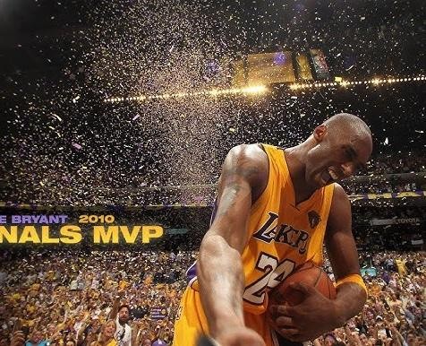 Dynamiczne ujęcie Kobego Bryanta w akcji podczas meczu NBA, wykonującego charakterystyczny rzut z odchylenia, z rozmytym tłem boiska i publiczności.
