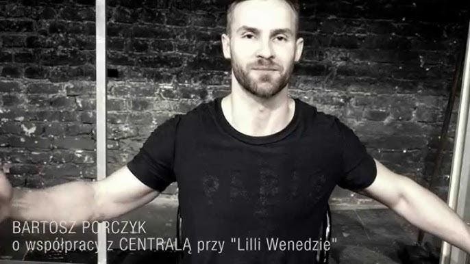 Bartosz Porczyk na scenie teatralnej podczas próby lub przygotowań do spektaklu, w dynamicznej pozie, ukazującej jego zaangażowanie w pracę aktorską.