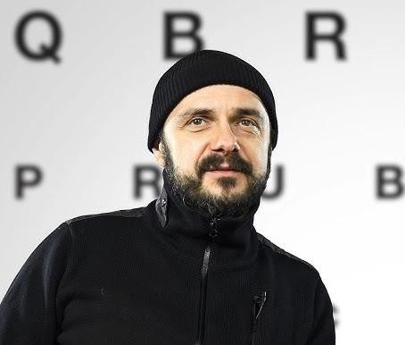 Arkadiusz Jakubik, wokalista zespołu Dr Misio, podczas energicznego występu na scenie, śpiewający do mikrofonu.