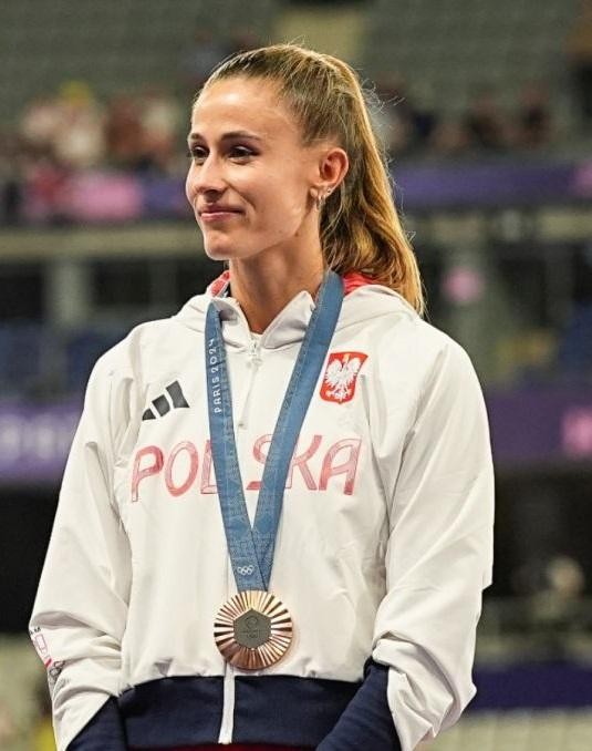 Natalia Bukowiecka na mecie biegu na 400 metrów, zdeterminowana, w otoczeniu rywalek i atmosfery stadionu.