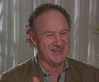 Gene Hackman na planie filmowym, w trakcie intensywnej pracy, oddający charakterystyczną dla siebie charyzmę i zaangażowanie w rolę.