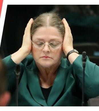 Krystyna Pawłowicz podczas wystąpienia publicznego w parlamencie lub sądzie, ukazująca jej zdecydowaną i wyrazistą postawę.